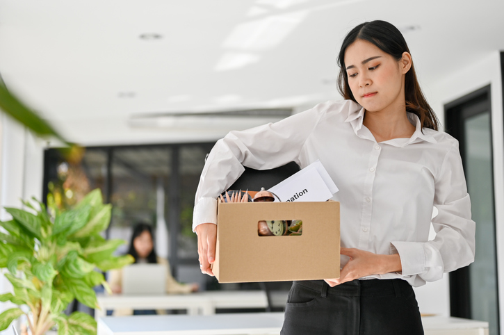Sad Asian female office worker carrying her belonging, quitting a job, being fired from her boss. western-copper-and-gold-layoffs-know-your-rights